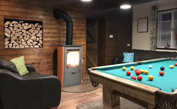 A cosy wood-panelled lounge with a warming stove and pool table